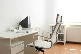 Une chaise de bureau moderne et ergonomique avec une surface d’assise blanche est placée à côté d’un bureau blanc.