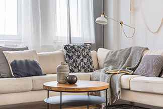 Choisir la bonne forme de table : un coin salon confortable devant lequel se trouve une table basse ronde avec un plateau en bois et un socle en métal noir.