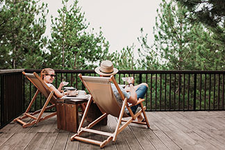 Utilisable à l'extérieur : sur un balcon, un homme et une femme sont allongés sur une chaise longue et boivent du thé – entre eux, une table d'appoint sur laquelle se trouve la théière.