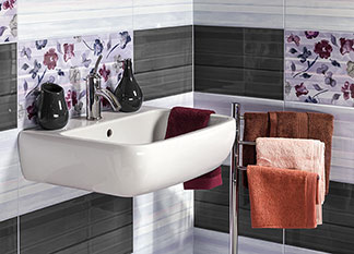 Un lavabo avec des carreaux fleuris, blancs et gris, crée une ambiance chaleureuse dans la salle de bains.