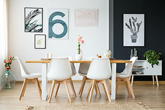 Il y a beaucoup de place sur la table à manger : dans une salle à manger, une table rectangulaire en bois se dresse entre six chaises à coques en plastique blanc et pieds en bois.