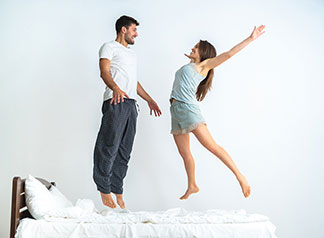 Une atmosphère de bien-être grâce à une grande qualité : une jeune mère est debout près du lit superposé de ses deux enfants qui sont assis sur le matelas et lisent un livre ensemble.