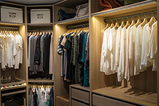 Le bon éclairage d'armoire : plusieurs lampes d'armoire éclairent l'intérieur d'une grande armoire à vêtements ouvertes.