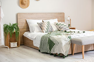 Il y a beaucoup de place dans le lit : de jeunes parents souriants sont allongés dans un grand lit recouvert de draps gris – leur bambin entre eux deux.