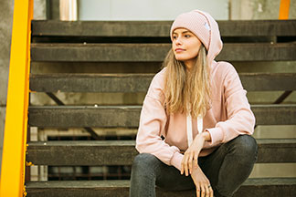 Un look street stylé et décontracté composé d‘un sweat femme à capuche, d‘une casquette, d‘un jean et de chaussures de sport.