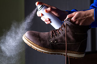 Gros plan sur une botte pour hommes en cuir qui est en train d’être recouverte d’un spray.
