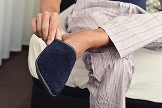 Des chaussons pour hommes de qualité : gros plan sur un homme en pyjama en train d'enfiler ses chaussons.