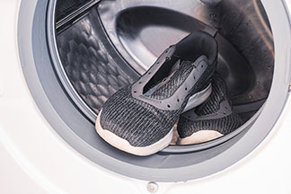 Entretenir correctement ses chaussures basses pour hommes : des baskets grises dont les lacets ont été retirés posées dans une machine à laver.