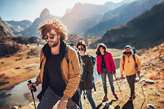Un groupe de jeunes gens portant des vêtements d'extérieur font une randonnée dans un paysage montagneux.