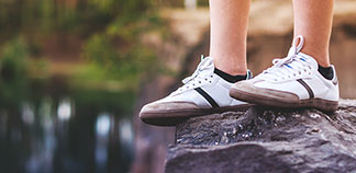 Des bas hommes sportifs : gros plan des jambes d'un jeune homme portant des baskets blanches et des chaussettes noires pour basket alors qu'il se tient debout sur un rocher.