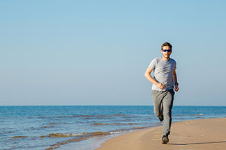 Un jeune homme se promène sur la plage dans un pantalon de jogging gris classique.