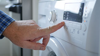 Laver correctement son gilet hommes : gros plan sur la main d'un homme qui allume une machine à laver.
