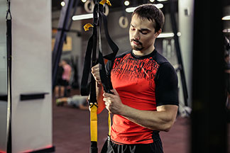 Un homme sportif portant un t-shirt de sport coloré ajuste un équipement de gymnastique.