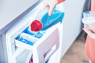 Le bon entretien pour votre écharpe hommes : gros plan d'un lave-linge rempli d'un détergent liquide.